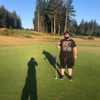 Special Olympics BC golfer standing next to a hole