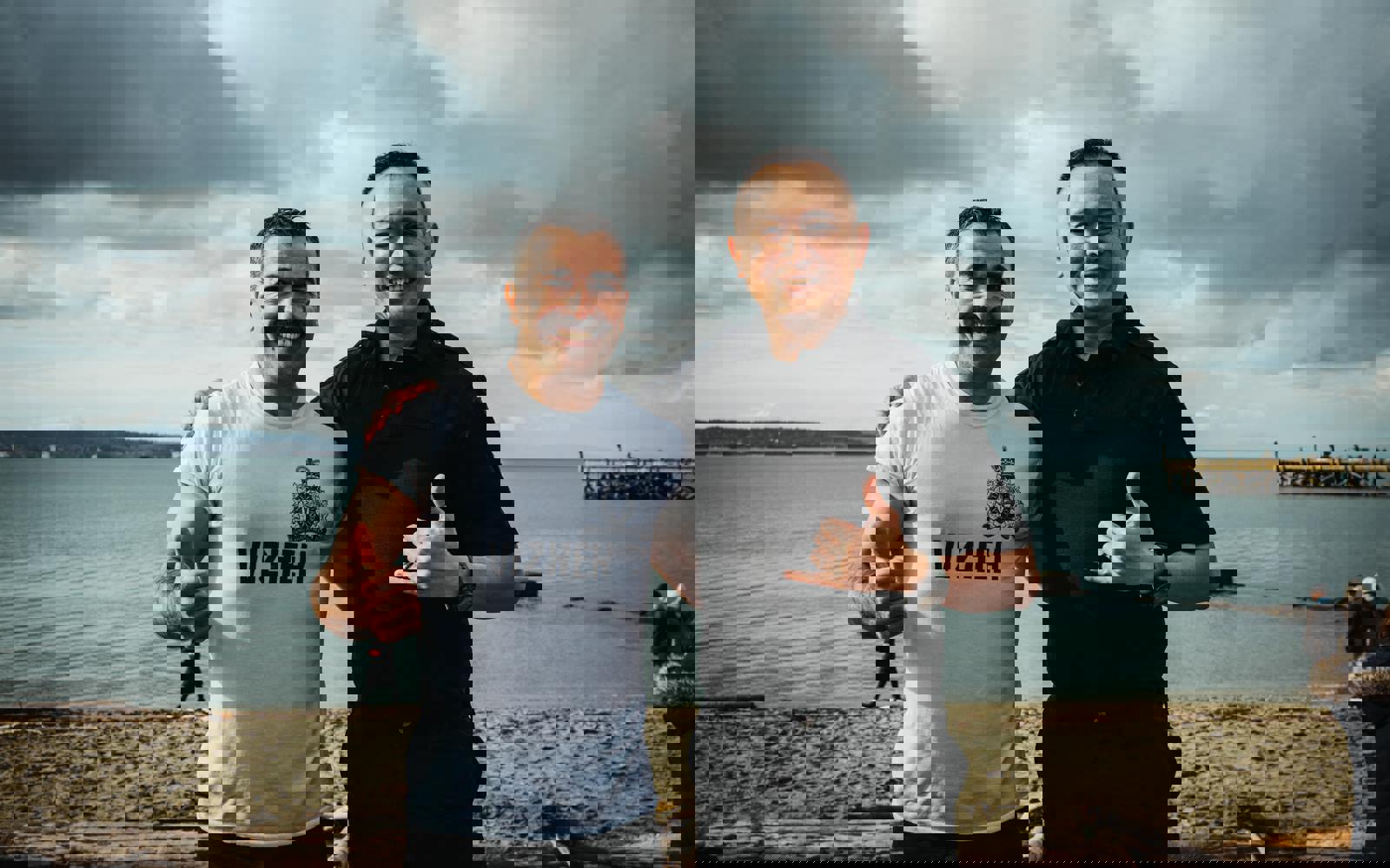 Two RCMP officers post on the beach with their thumbs up.