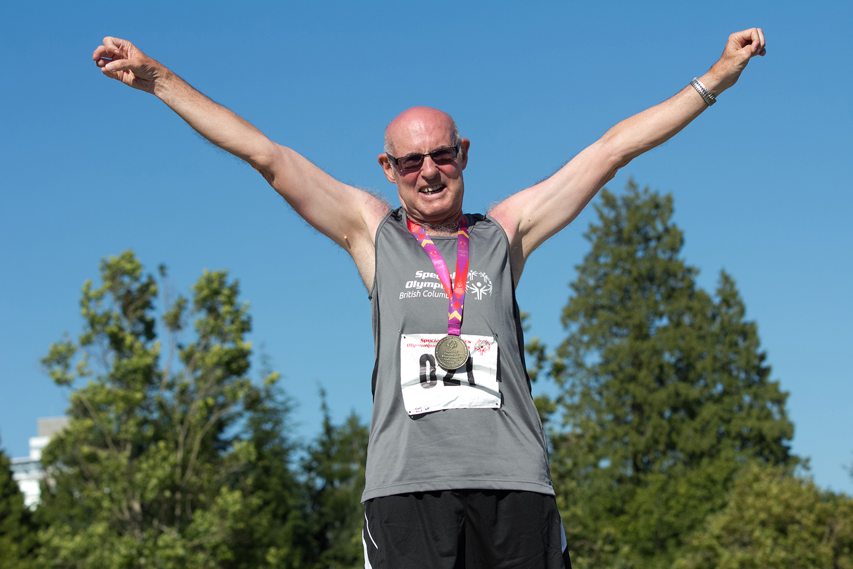 Special Olympics BC athlete celebrates his podium finish with arms raised and a big smile at the 2014 Special Olympics Canada Games. Special Olympics BC athlete celebrates his podium finish with arms raised and a big smile at the 2014 Special Olympics Canada Games.