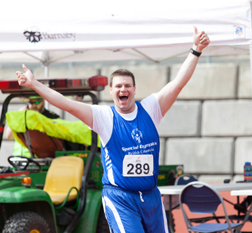 Special Olympics BC athlete gives an energetic two-thumbs up to the camera at a track and field meet.