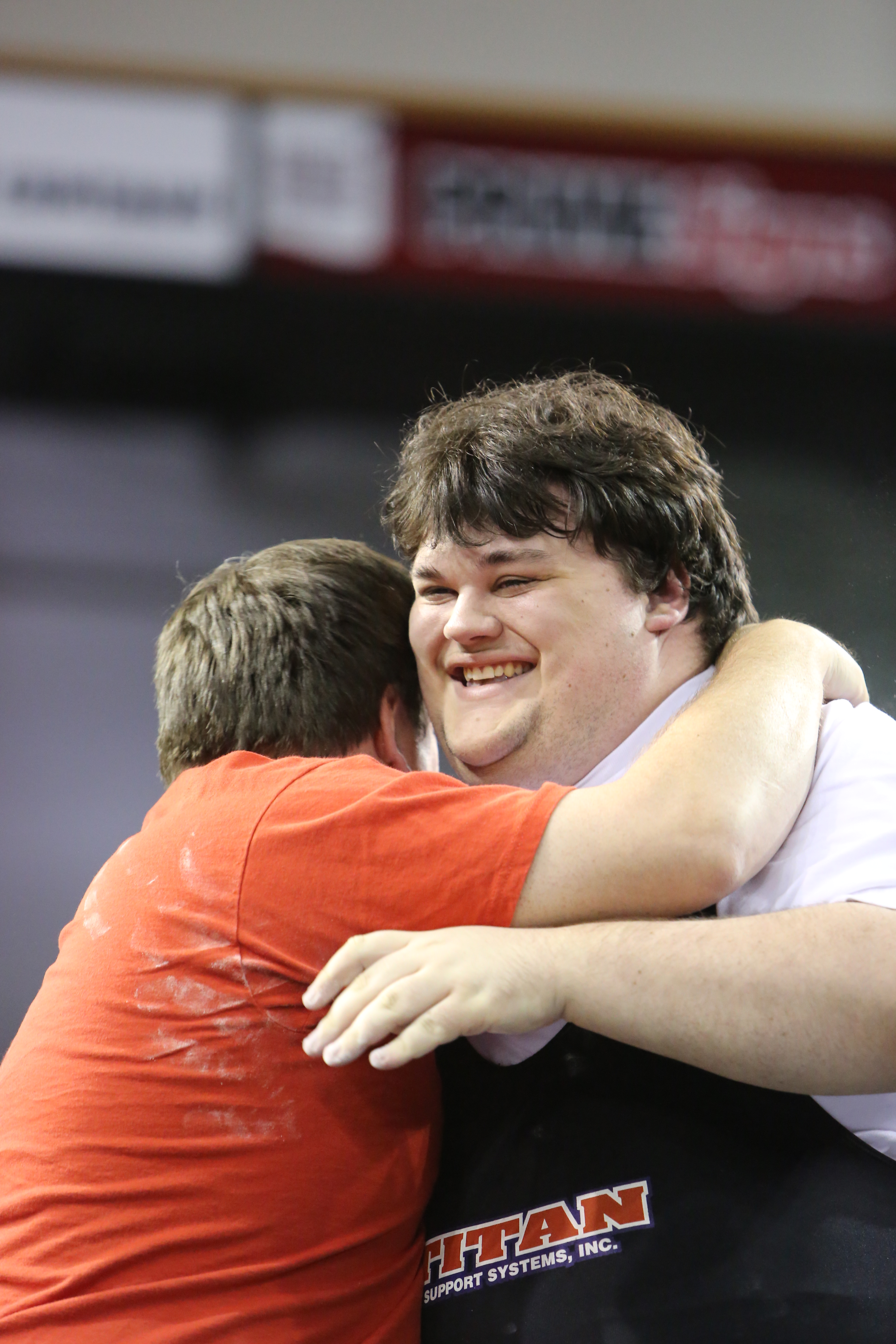 A powerlifting athlete smiles and is embraced by his coach after a good lift. A powerlifting athlete smiles and is embraced by his coach after a good lift.