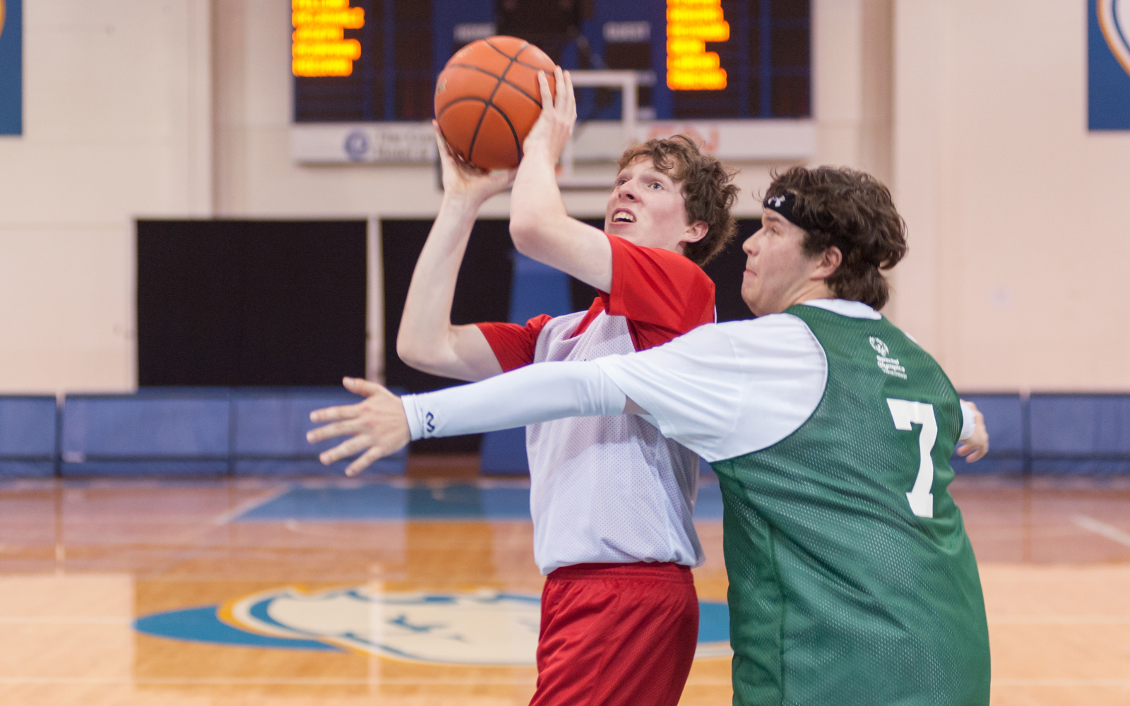 One Special Olympics BC basketball athlete plays defense against another athlete attempting to shoot the ball.