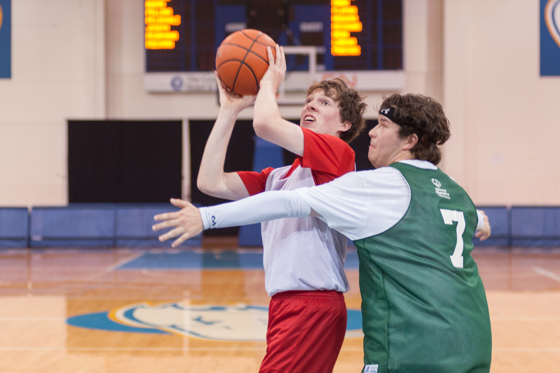 One Special Olympics BC basketball athlete plays defense against another athlete attempting to shoot the ball.