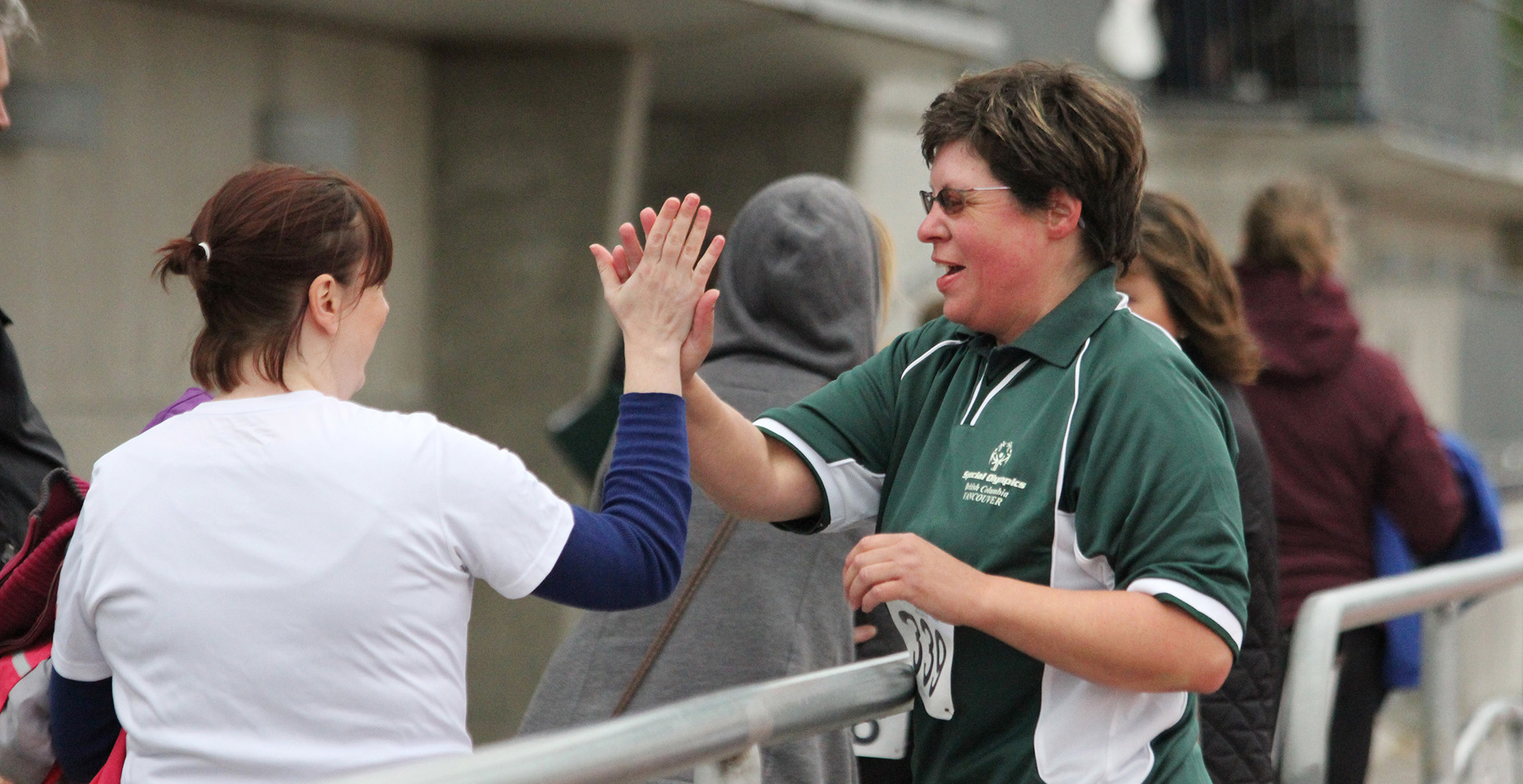 Special Olympics BC athlete high fives a fellow athlete after their race.