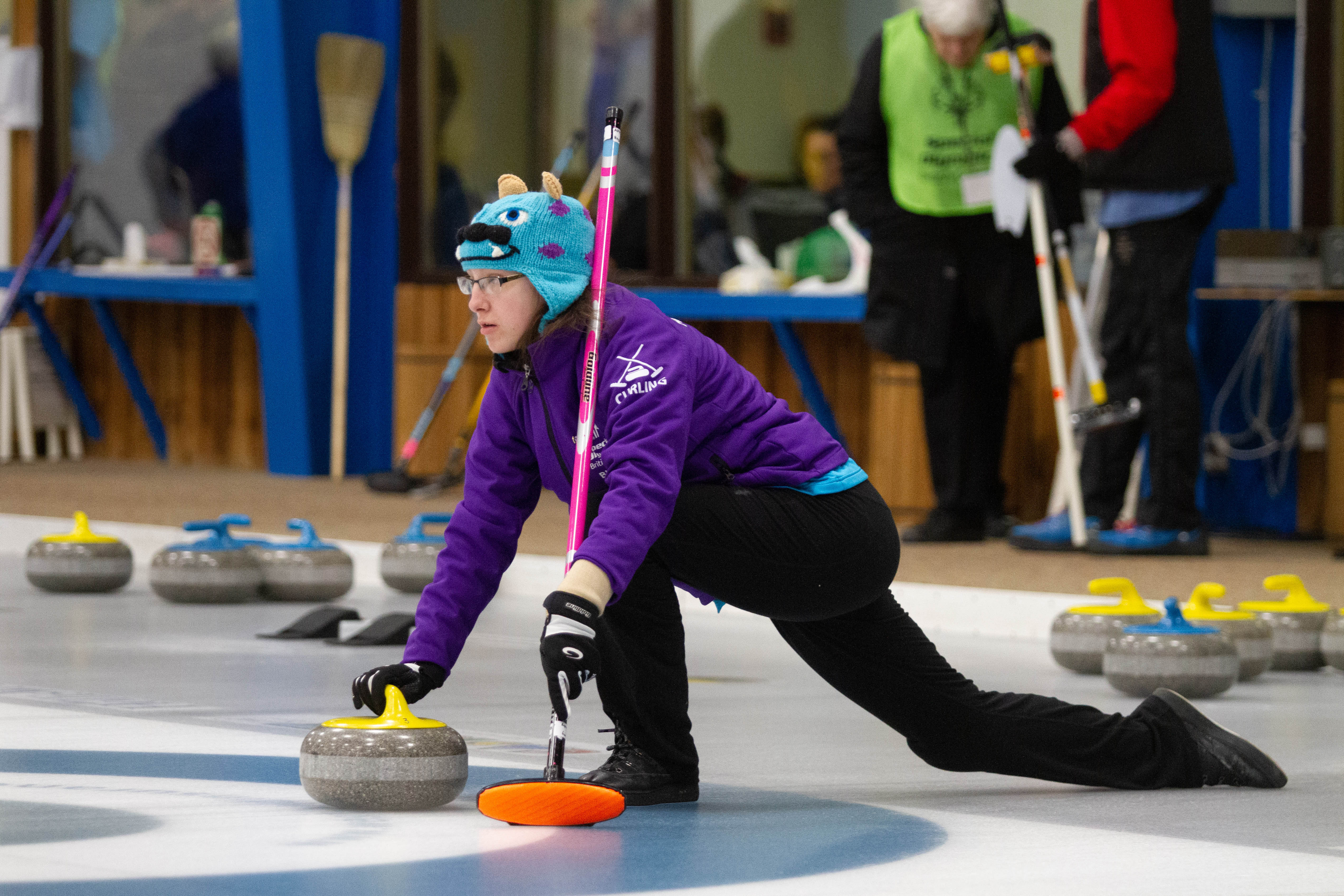 Special Olympics BC curling athlete positions herself with her broom and rock to prepares for her throw down the rink.