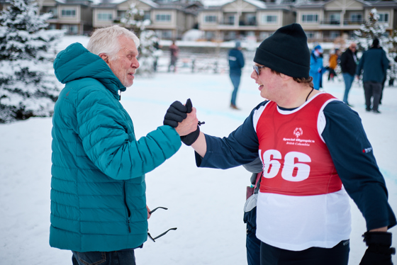 A snowshoeing athlete high fives his coach.