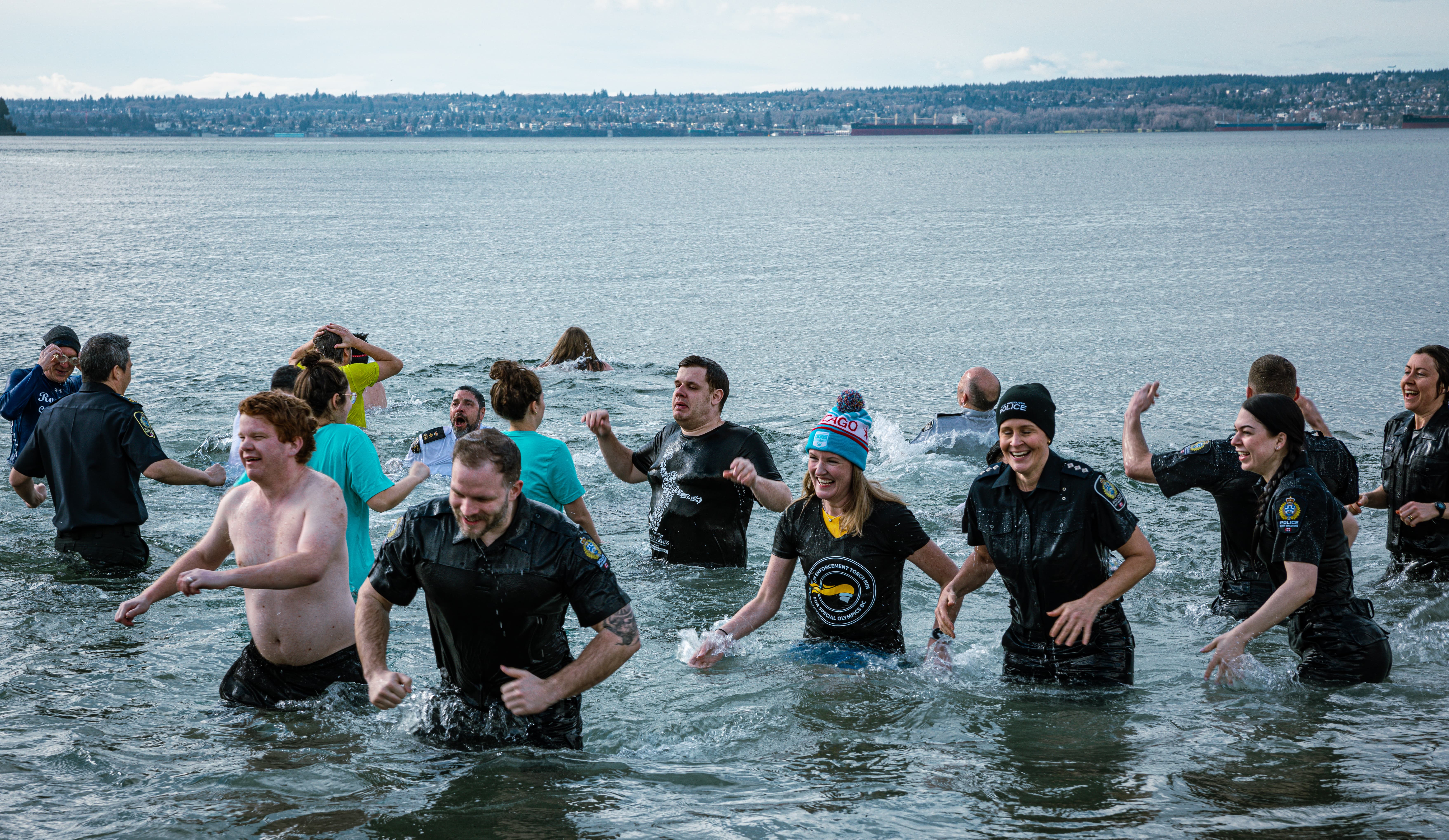 A large group of Law Enforcement Torch Run Polar Plunge participants wade out of the frigid waters with smiles on their faces.