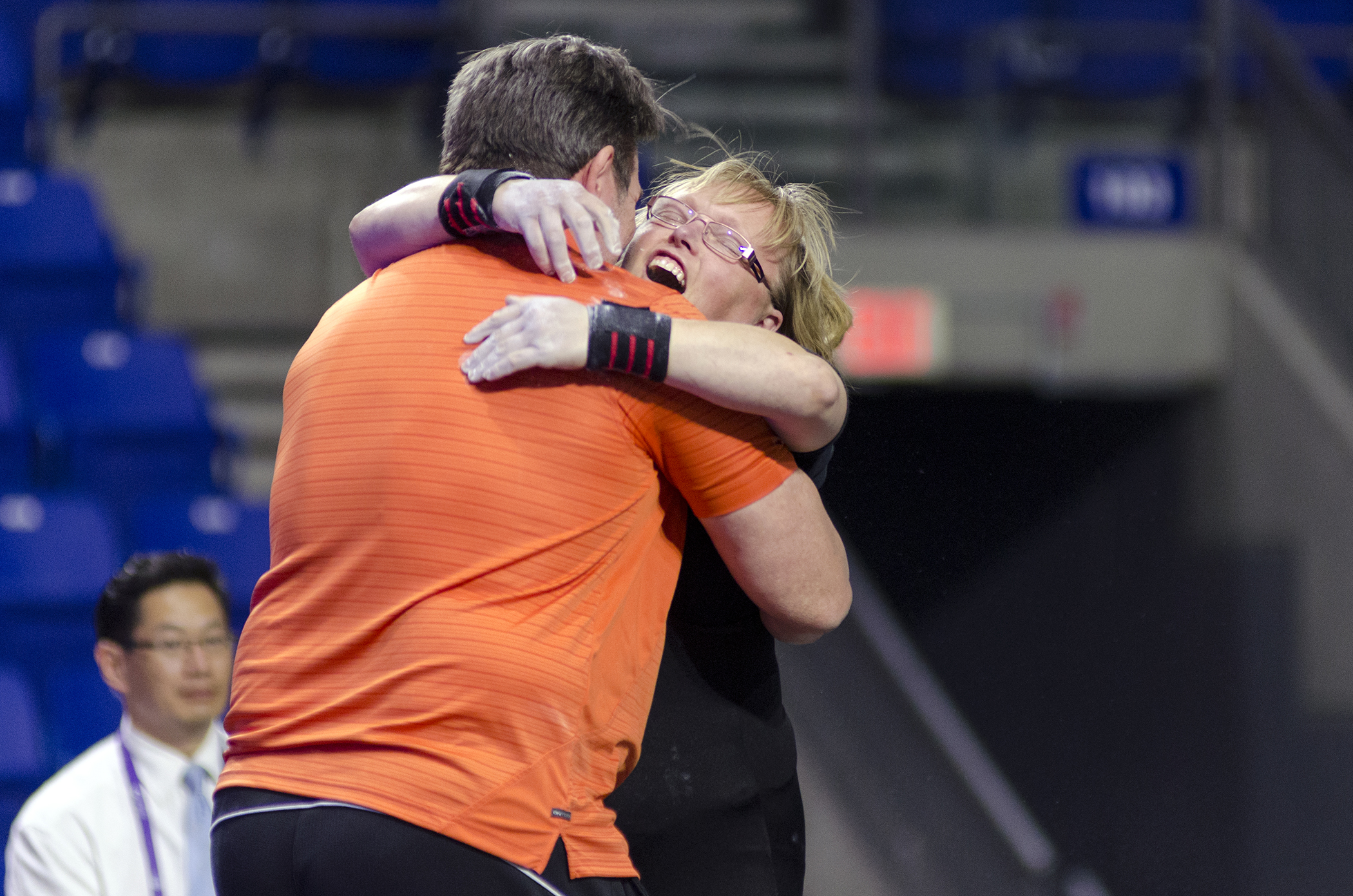 A coach and powerlifting athlete embrace at a competition.