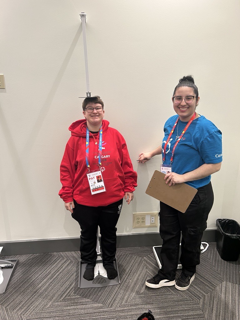 An athlete gets their height checked by a volunteer.