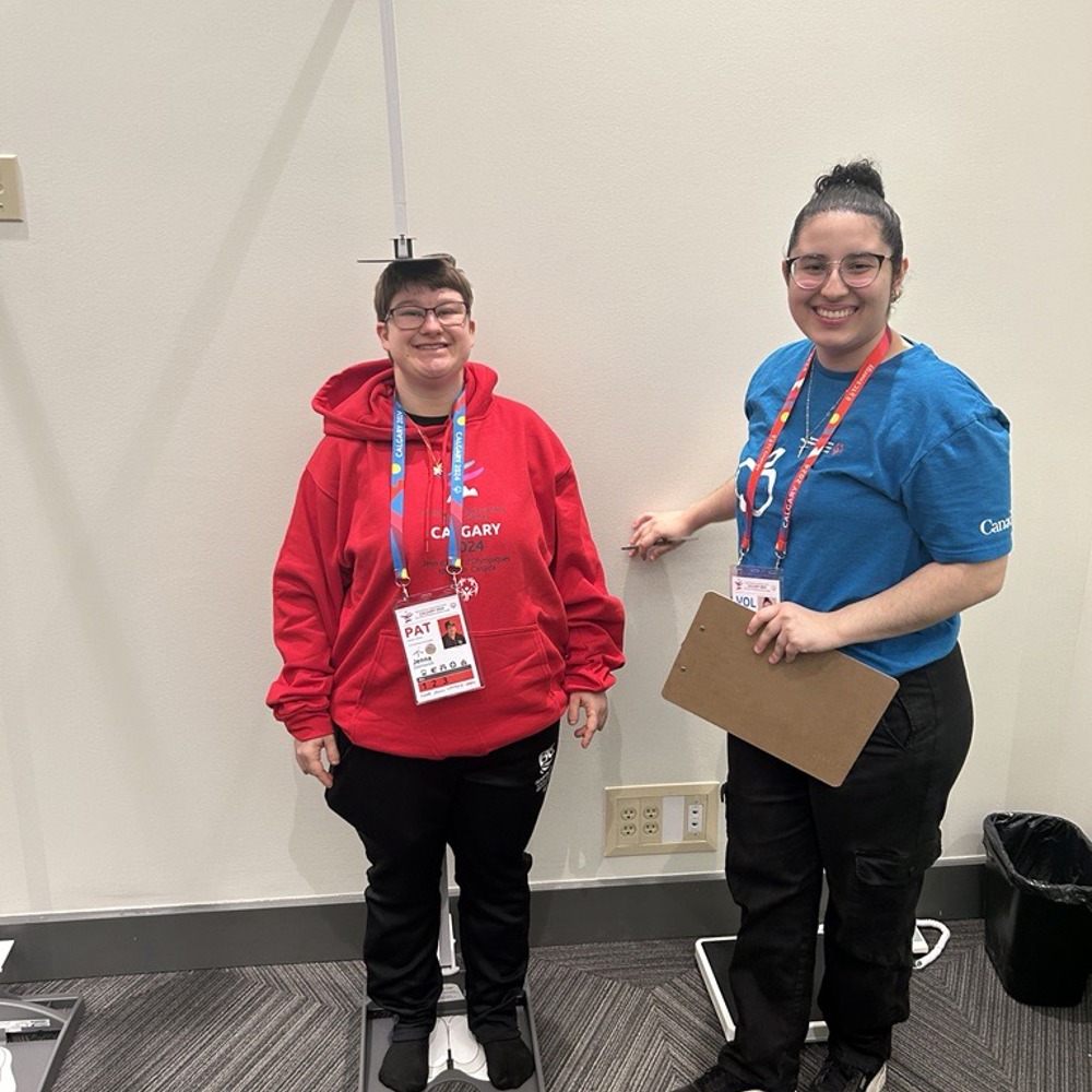 An athlete gets their height checked by a volunteer.